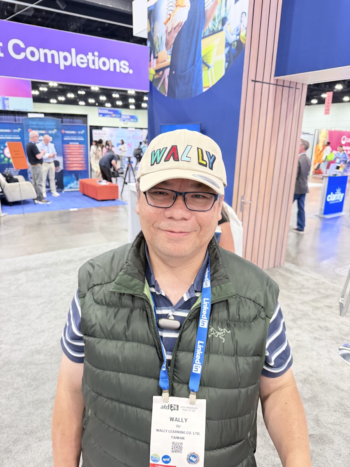 Guest wearing a custom chenille-letter cap on a busy convention floor