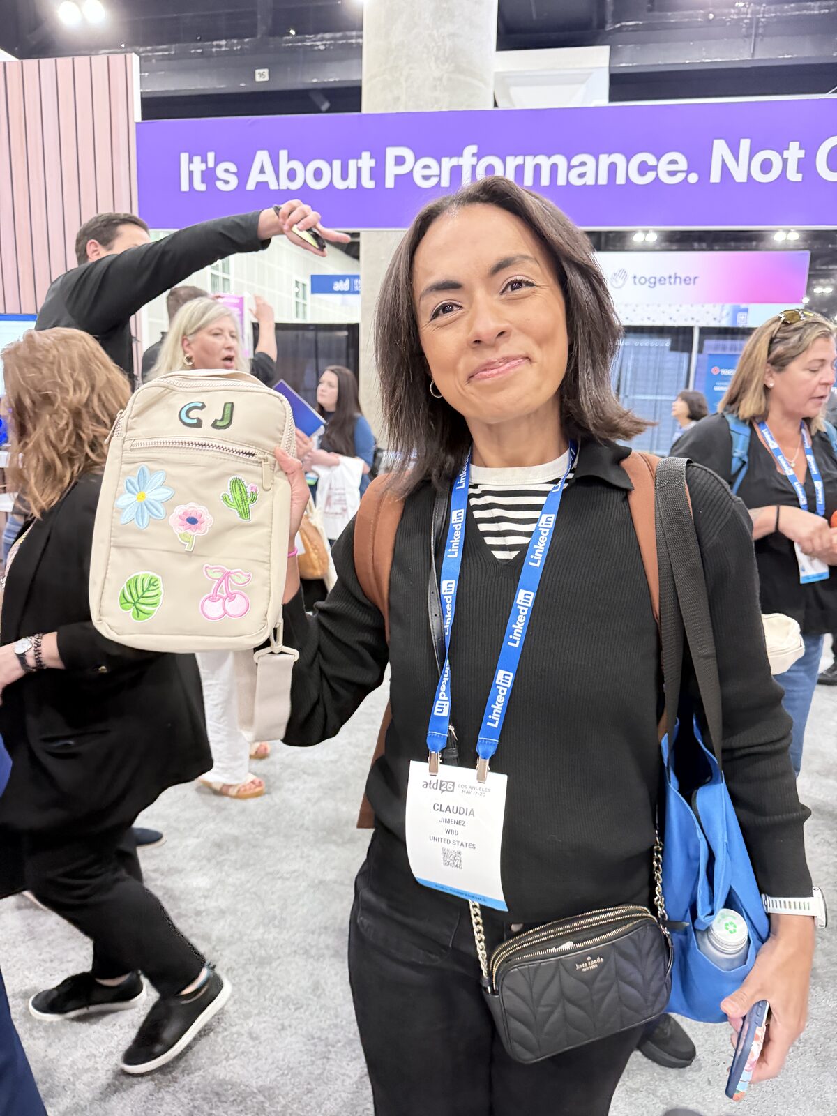 Conference guest holding up a personalized patch bag with her initials on the trade-show floor