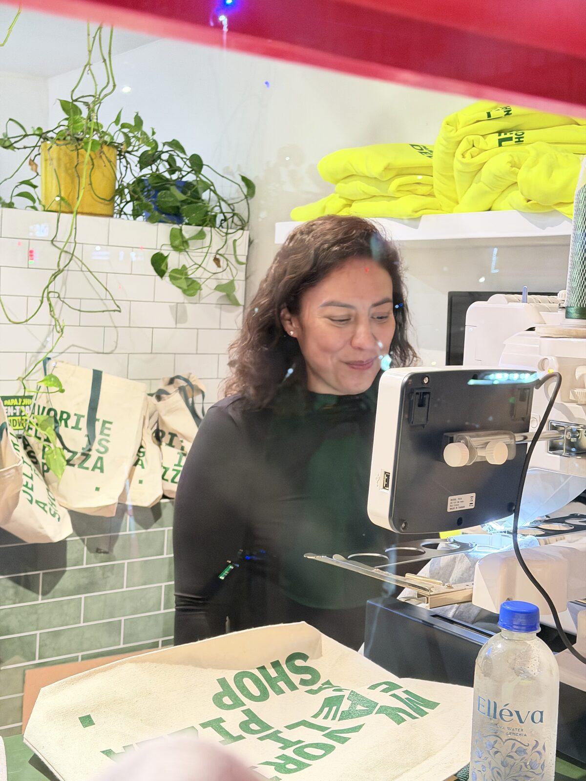 Crew member running a live tote-bag personalization station with canvas totes hanging behind her