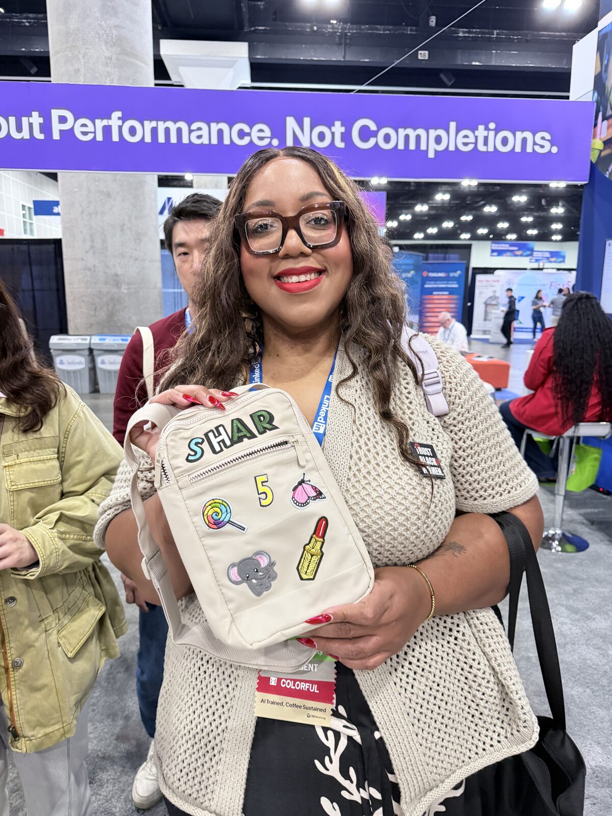 Smiling conference guest holding up a custom patch bag with her name in chenille letters