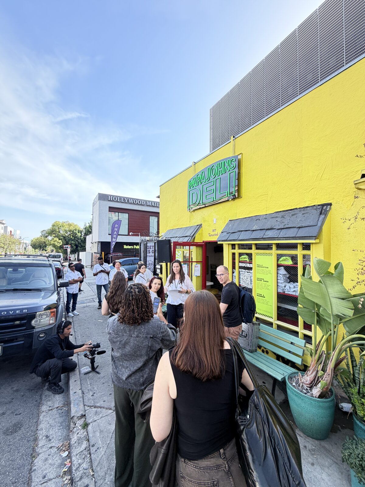 Crowd gathered on the sidewalk outside a bright yellow pop-up storefront